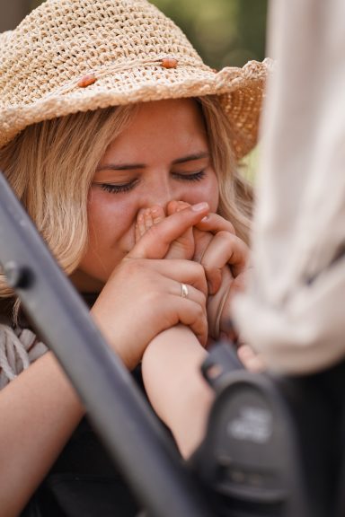 Frau mit Strohhut, die nachdenklich ihre Hände hält, in einem entspannten Umfeld.